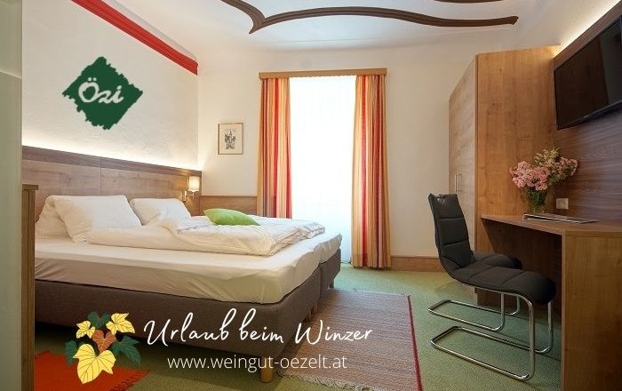 Guest room, © DM Cozy guest room with double bed, desk and chair, decorated with flowers. Light-colored curtains and carpeted floor.