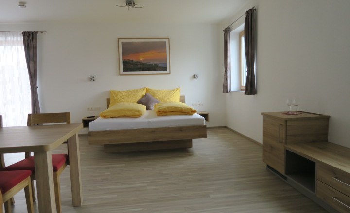New guest room, © ettenauerweine Modern guest room with double bed, wooden furniture and yellow cushions.