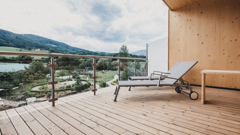 Recharge your batteries in Kirchberg am Wechsel, © Heldentheater, Hotel Molzbachhhof Wooden terrace with sun lounger and view of the green landscape and mountains.