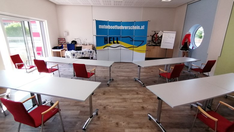 Training room at the Karl Hell School of Navigation, © Schiffsführerschule Ing. Karl Hell Training room with tables and chairs, Hell skipper school banner, flipchart and mannequin.