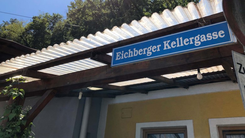 Eichberg wine cellar lane, © Donau Niederösterreich Sign with the inscription 'Eichberger Kellergasse' on a building with a corrugated iron roof.