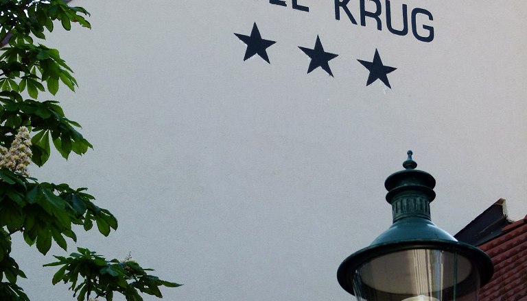 Main picture, © martina krug Facade of the Hotel Krug with three stars, tree and street lamp.