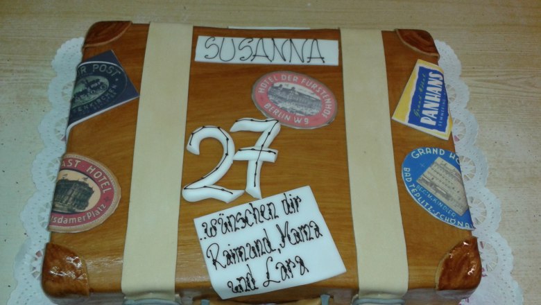 Cake bakery, © Konditorei Köller A cake in the shape of a suitcase with stickers and the number 27.