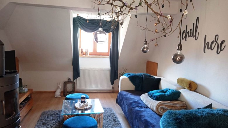 Nazbauerhof - Living room, © Christina Becker Cozy living room with sofa, blue carpet, decorative branches and 'chill here' lettering.