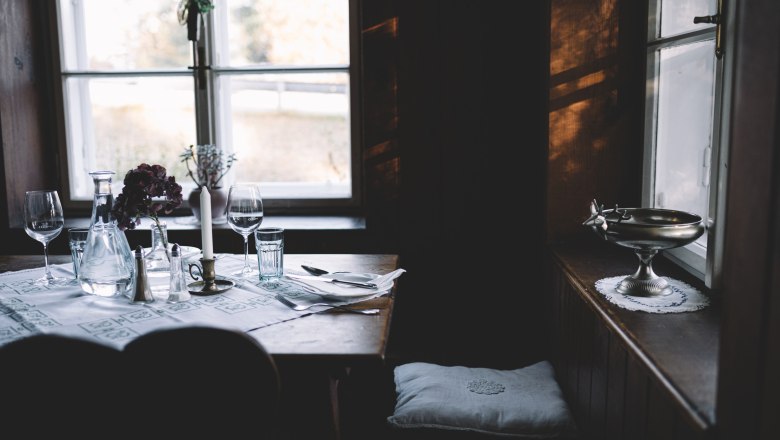 Popular in the rustic parlor: dumplings, game, offal, © Niederösterreich Werbung/Mara Hohla A cozy table setting in a rustic parlor with candles and wine glasses.