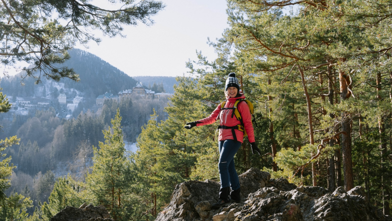 Cultural hike to the Doppelreiterwarte, © Luxusgämsen Person in pink jacket walking on a rocky path in the forest with mountains in the background.