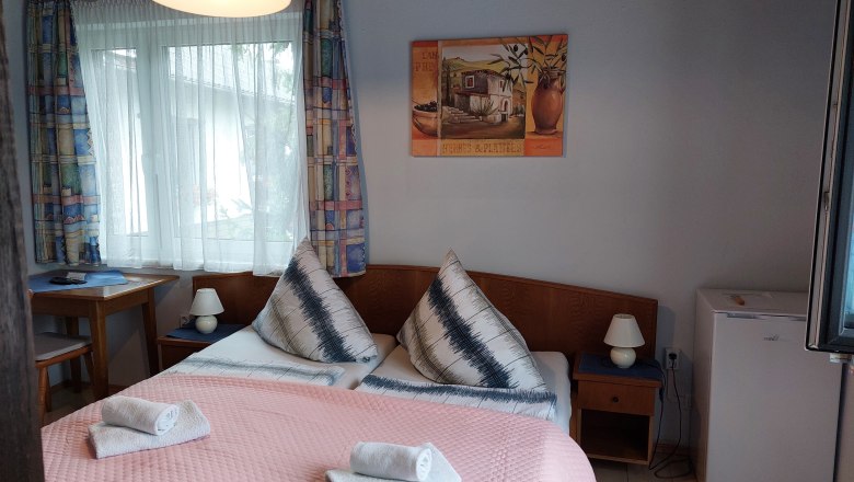 TDR-Pension Welserhof, © Bartfai Comfortable hotel room with double bed, bedside lamps, small fridge and window with curtains.