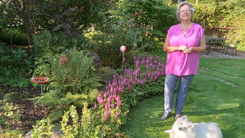 dagmar-and-keke, © Dagmar Scheucher A woman stands in a garden next to a white dog on the lawn.