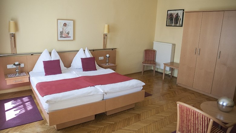 Königsbrunner Landgasthof Mann, © Simon Jappel Hotel room with double bed, wooden furniture and red accents.