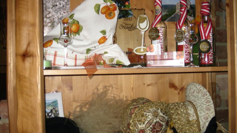 Radlerhof Kienesberger, © Kienesberger Wooden shelf with decorations, liqueur bottles and hats.
