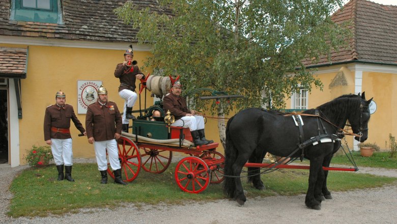 Lanzenkirchen Fire Brigade Museum, © Gemeinde Lanzenkirchen Historic fire engine with horse and firemen in uniform in front of a yellow building.