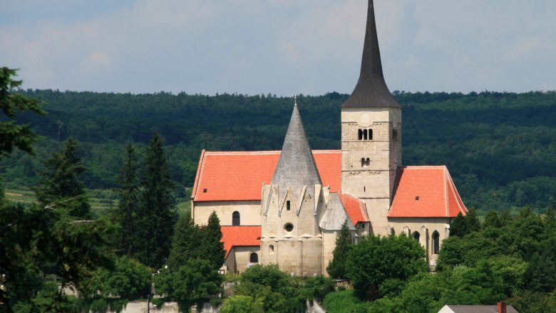 St. Michael's Church in Pulkau, © Fotoclub Pulkau St. Michael's Church in Pulkau with a red roof and pointed tower, surrounded by trees.
