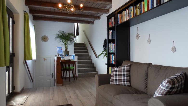 Entrance area, © Ullram Living room with brown sofa, bookshelf and staircase in the background.