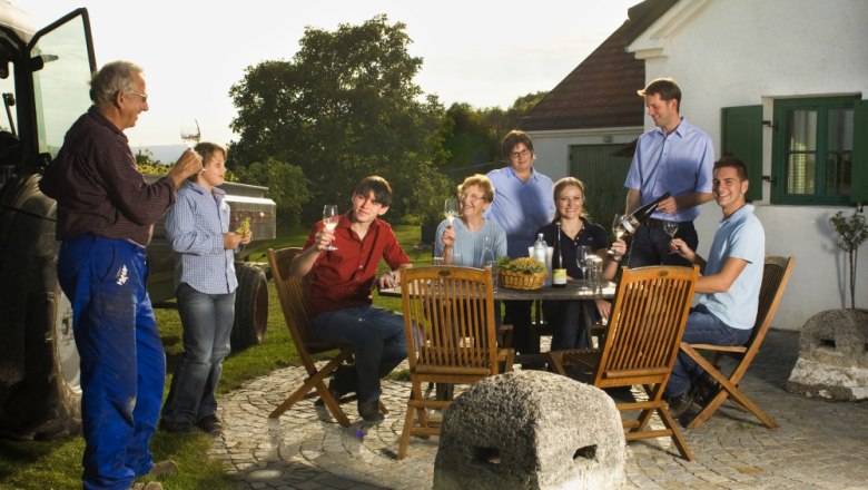 Wine tavern in the vineyard, © Johannes Kitzler Group of people sitting outside at a table with wine and snacks.