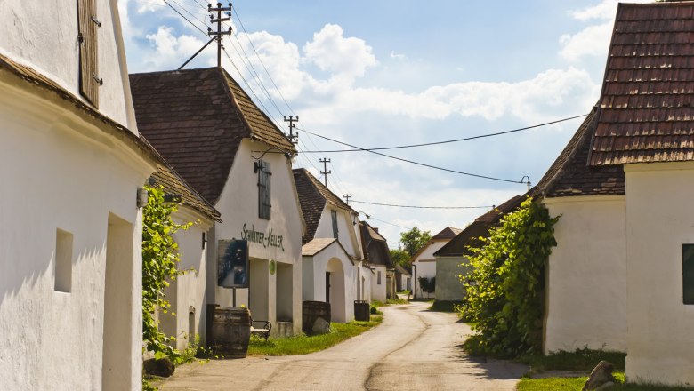 Wine cellar lane, © Gemeinde Zellerndorf A picturesque wine cellar lane with white buildings and tiled roofs under a blue sky.