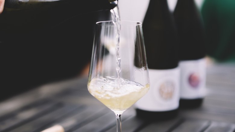 Pouring wine, © Niederösterreich Werbung / Mara Hohla White wine is poured into a glass on a table.