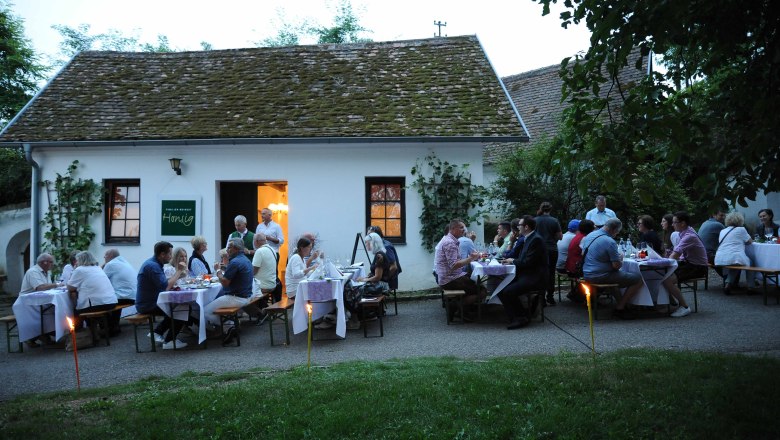 Cellar from the Honsig Winery, © H. Schleich People sit in front of a wine cellar in the evening and enjoy a meal outdoors.
