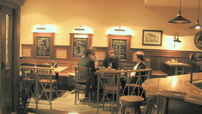 Braugasthof Adlerbräu, interior view, © Braugasthof Adlerbräu Interior view of a cozy inn with wooden furniture and three people at a table.