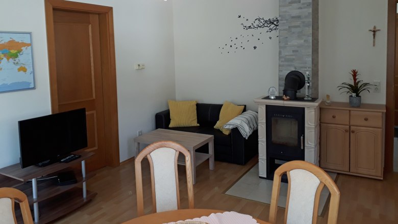 Eat-in kitchen, © Barbara Muck Living room with fireplace, sofa, table and TV.