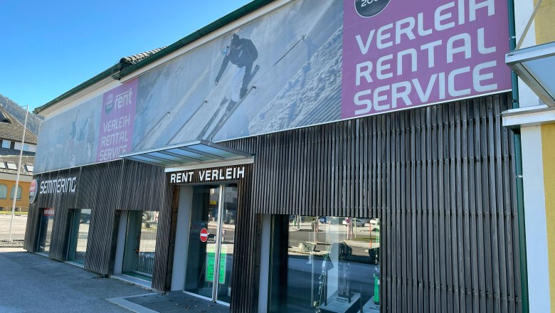 Sport-Puschi-Service, © Sport Puschi Exterior view of a sports rental store with large advertising banners and shop windows.