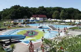 Parkbad Bruck/Leitha, © Wolfgang Stinauer Outdoor pool with several pools, slide and sunbathing lawn, surrounded by trees.