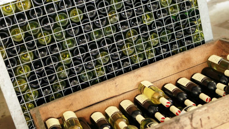Heurigen restaurant Schabasser family, © weinfranz.at Wine bottles in a lattice rack and a wooden crate.