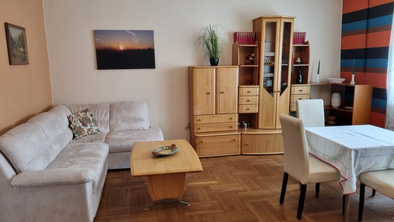 House Waschbergblick, © Wolfgang Greil Living room with beige couch, wooden furniture and dining table.