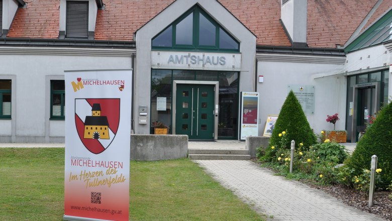 Municipality of Michelhausen, © Marktgemeinde Michelhausen Entrance to the Amtshaus Michelhausen with advertising banner and well-tended garden.