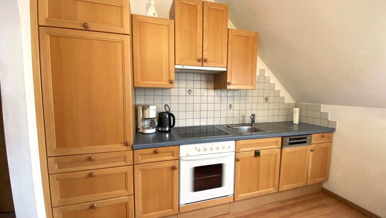 Vacation apartment Traube, © Trachsler Kitchen unit with wooden cupboards, stove, sink and tiled splashback.