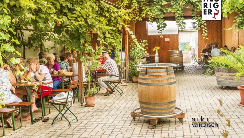 Wine tavern Windisch, © Weingut Windisch / A. Seidl A cozy wine tavern with guests under an arbor of vines.