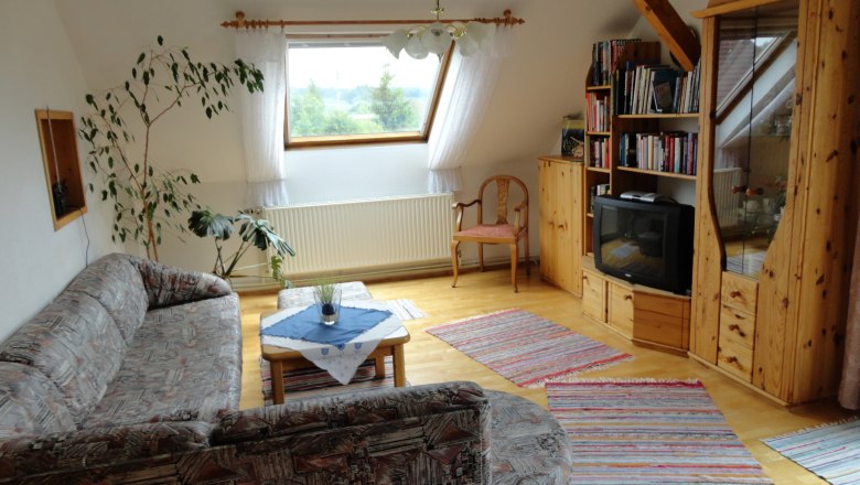 Guesthouse Reuberger, © Gästehaus Reuberger Cozy living room with sofa, wooden furniture and TV.