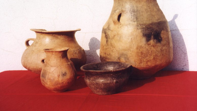 Museum, © Wienerwaldmuseum Four antique clay vessels on red cloth in front of a white wall.