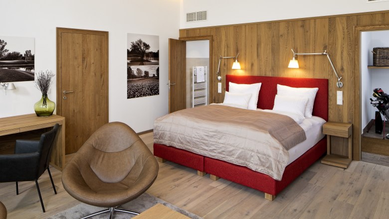 Diamond Country Club Diamond Room, © DCC Modern hotel room with red bed, wooden furniture and golf magazines on the table.