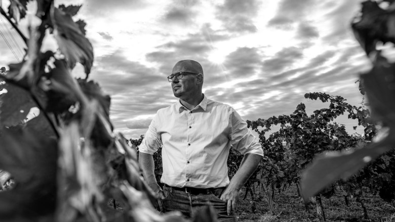 Jassek_Weingarten(c)MartinLifkaPhotography_OK_780x440, © Martin Lifka Photography Black and white photo of a man in a vineyard with a cloudy sky in the background.