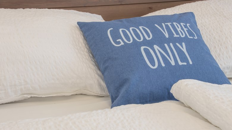 Double room Fuchs, © A. Dirnbauer Bed with blue cushion, inscription 'Good Vibes Only'.