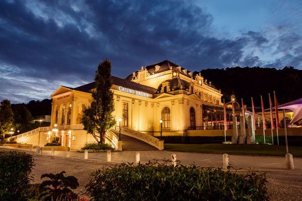 Casino Baden, © Casinos Austria AG Illuminated Casino Baden at night with a dramatic sky.