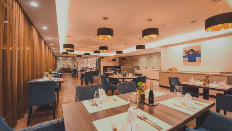 Restaurant, © NMC Elegant restaurant with laid tables, blue chairs and modern lighting.