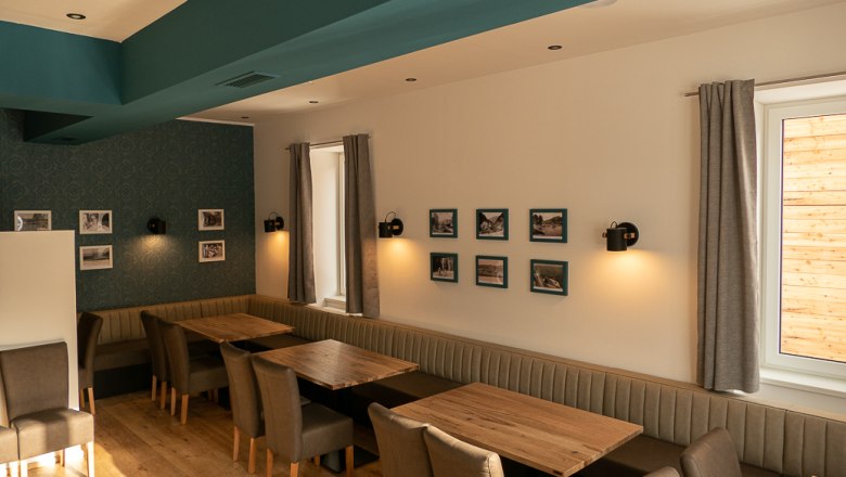 Restaurant Piestingerhof, © Sara Grill Interior view of a restaurant with wooden tables, upholstered benches and chairs, decorated with pictures on the walls.