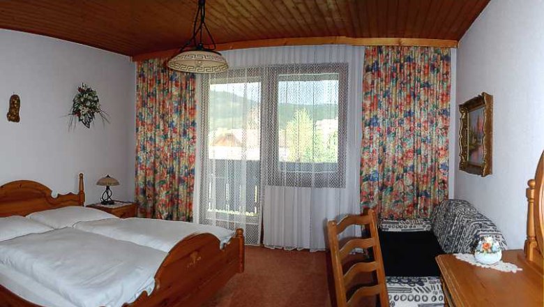 Angerhof room, © Buchinger Comfortable hotel room with wooden furniture, double bed, balcony and colorful curtains.