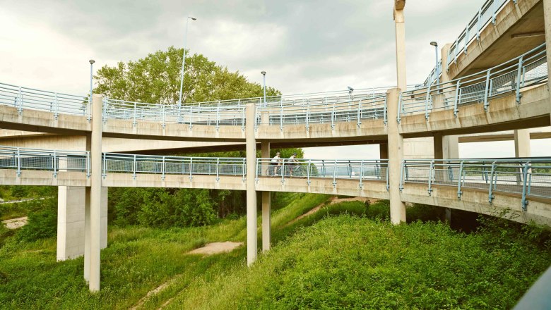 Cycle path helix, © Klaus Engelmayer A multi-level bicycle ramp with blue railings in a green setting.