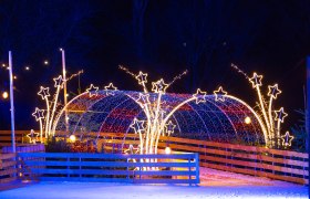 Ice skating rink in the Eis-Greissler Welt, © Blochberger Eisproduktion GmbH Illuminated ice rink with stars and tunnel of lights at night.