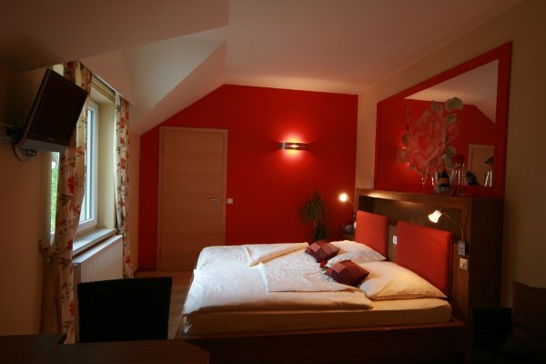 Premium bon-vivant rooms, © Rosenhotel Cozy bedroom with red wall and double bed.