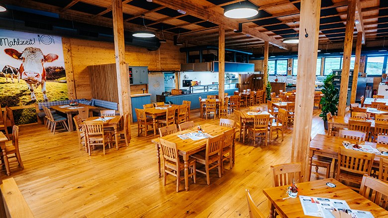 Eis-Greissler Culinary Stadl inside, © Blochberger Eisproduktion GmbH Rustic restaurant with wooden furnishings, square tables and chairs and pillars.