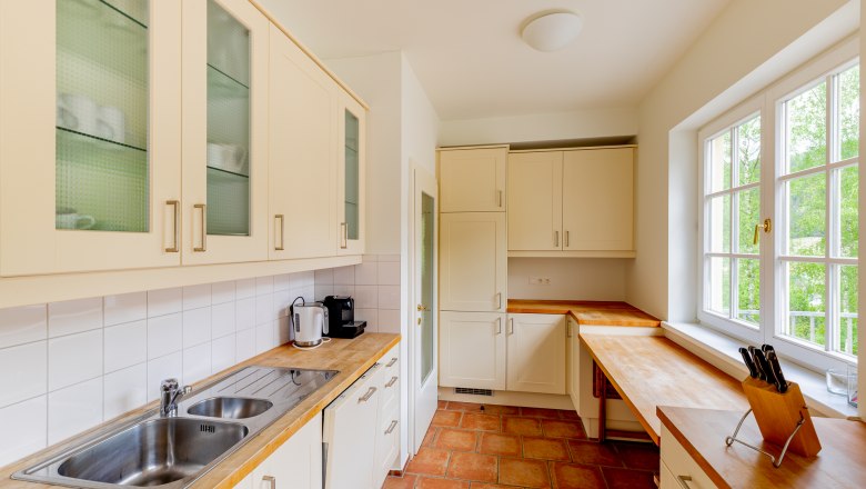 Kitchen, © Wiener Alpen / Christian Kremsl Bright kitchen with wooden worktops, white cupboards and large windows.