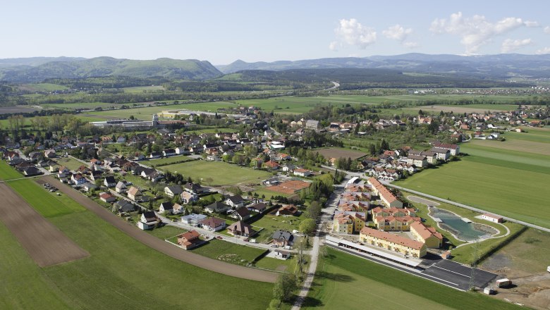 Breitenau, © Gemeinde Breitenau Aerial view of a village with fields and hills in the background.