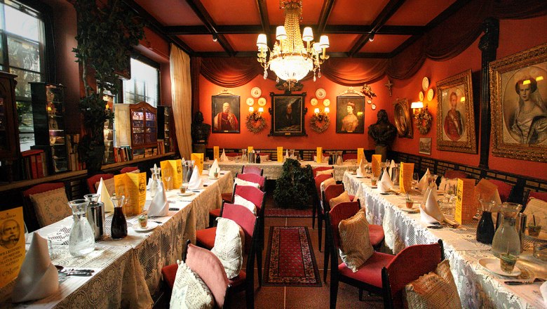 Marchfelderhof, © Gault Millau Elegant restaurant with long, laid tables, red walls and chandeliers.