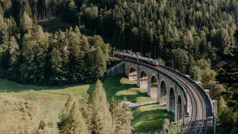 Semmering Railway, © wieneralpen,nicoleseiser.at A train crosses a viaduct, trees in the surroundings