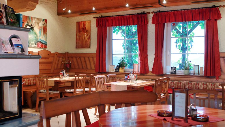 Tavern Hansbauer, © weinfranz.at Cozy interior of a traditional Austrian wine tavern with wooden furniture and red curtains.