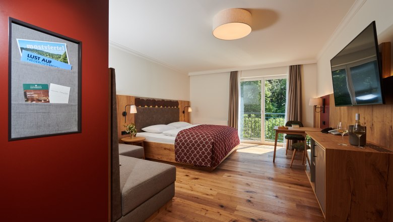 RelaxResort Kothmühle, © Dominik Stixenberger Hotel room with double bed, wooden floor, balcony and TV.