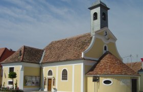 Wine church Jetzelsdorf, © Marktgemeinde Hhaugsdorf Yellow church with clock tower and 'Weinkirche' lettering.